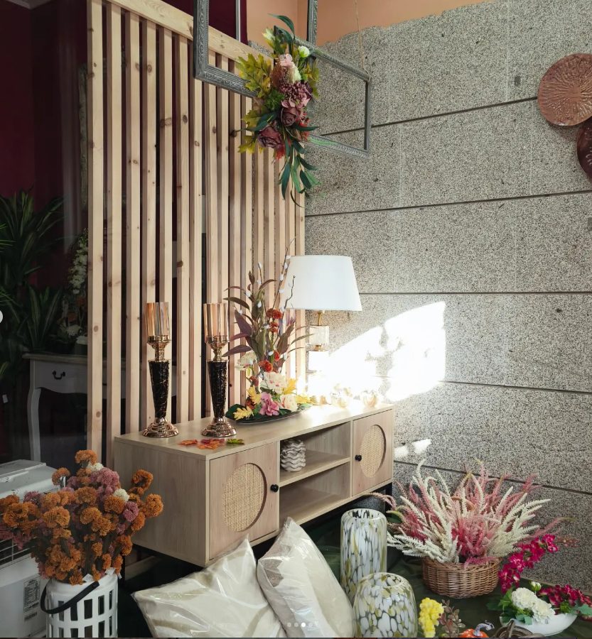 Composición de flores secas y plantas junto a una lámpara en el interior de la floristería